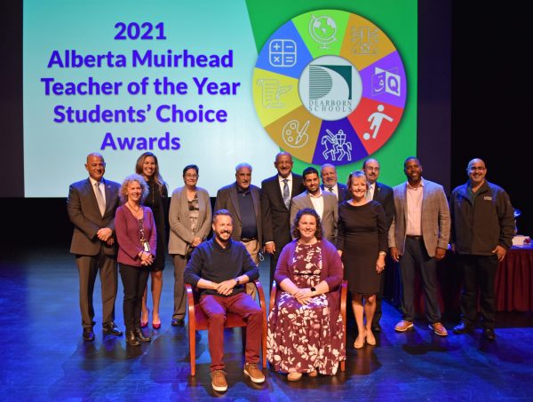 A group of people gathers in front of a screen for the 2021 Teacher of the Year Award.