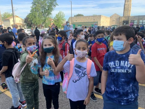 A group of elementary students in face masks give a thumbs up sign outside Oakman Elementary in August 2021.