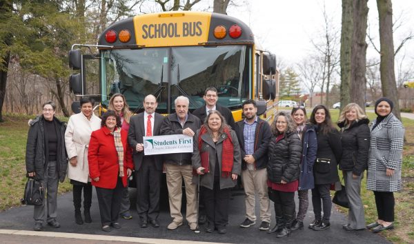 A group of elected officials and school representatives pose with a new electric bus during the bus' unveiling on Dec. 15, 2022.