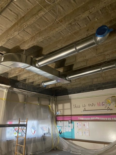 HVAC ducts are added to an exposed ceiling at Whitmore Bolles Elementary School.