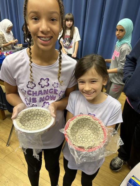 Two girls at Snow Elementary show off clay bowls they made for the Empty Bowls event on Nov. 13, 2023.