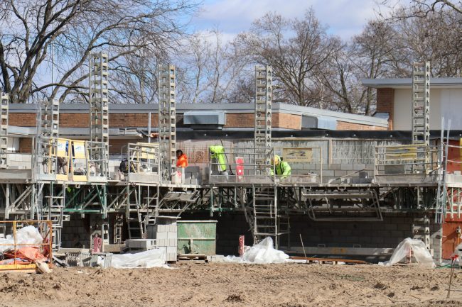 Construction workers build a wall at Haigh Elementary