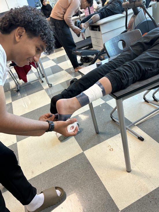 A student tapes another student's ankle during a sports medicine class at Michael Berry Career Center.