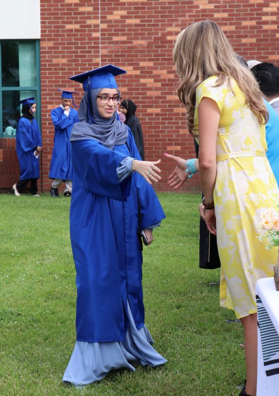 A Virtual K-12 graduate reaches to shake hands with an official