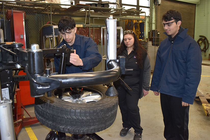 A Fordson High student uses a new tire changing machine while other students look on.